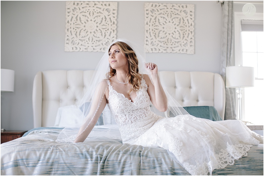 bride posing on bed before clarks landing yacht club wedding 