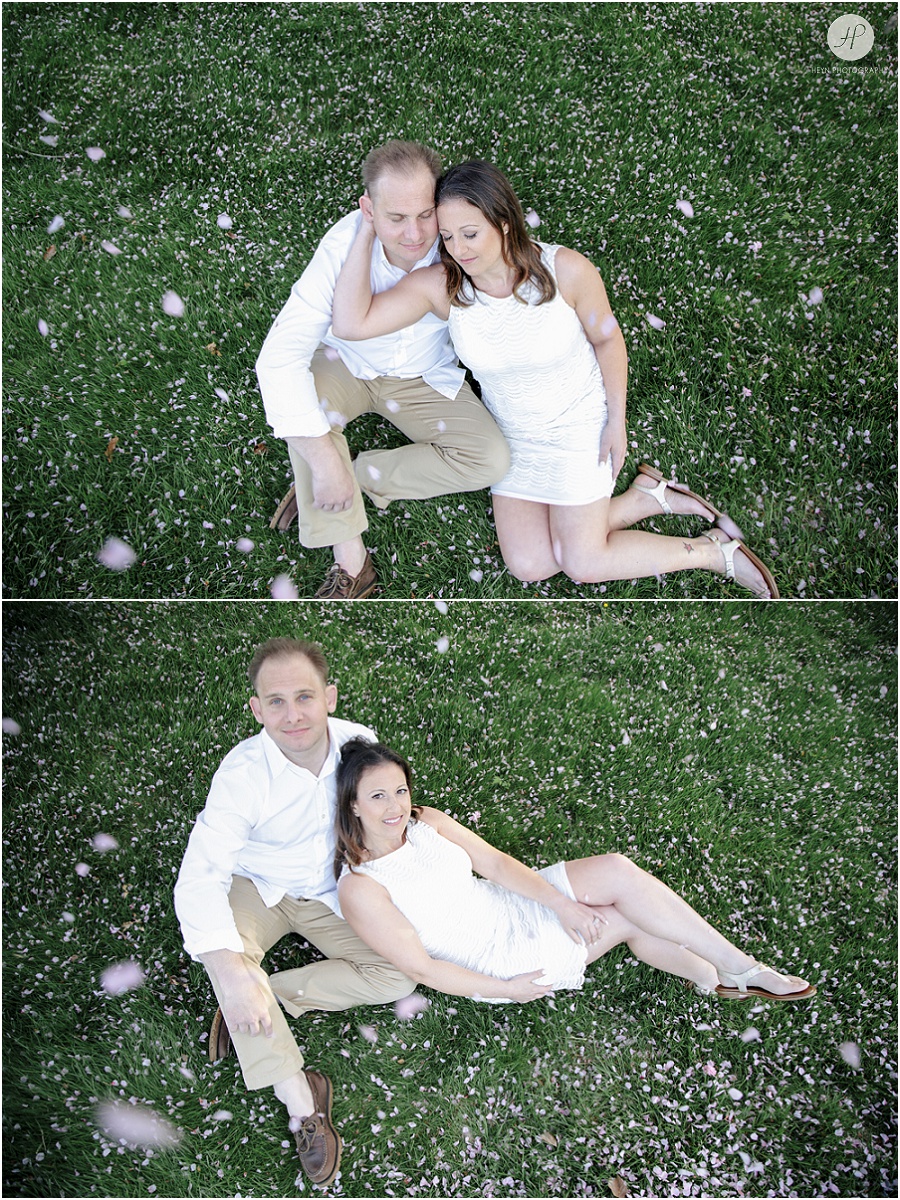 Couple sitting on grass under cherry blossom in Spring Lake engagement session