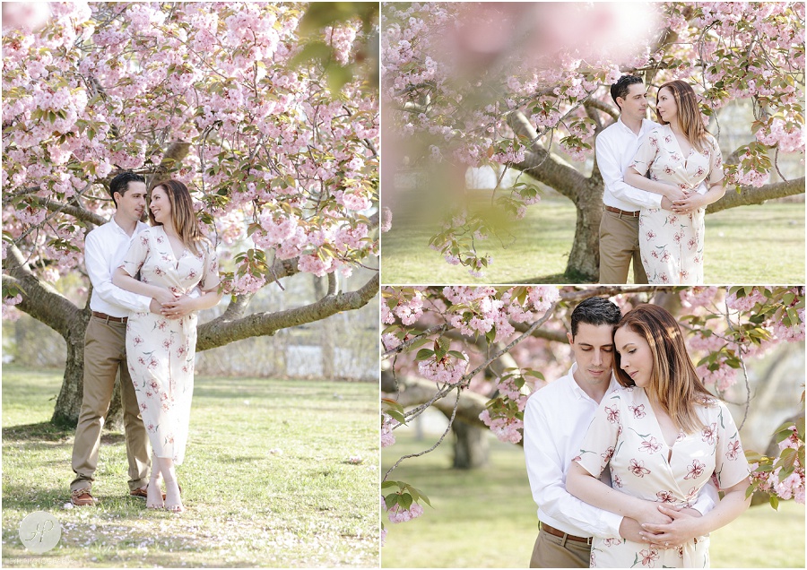 couple holding each other by cherry blossom tree at spring lake engagement session in new jersey 