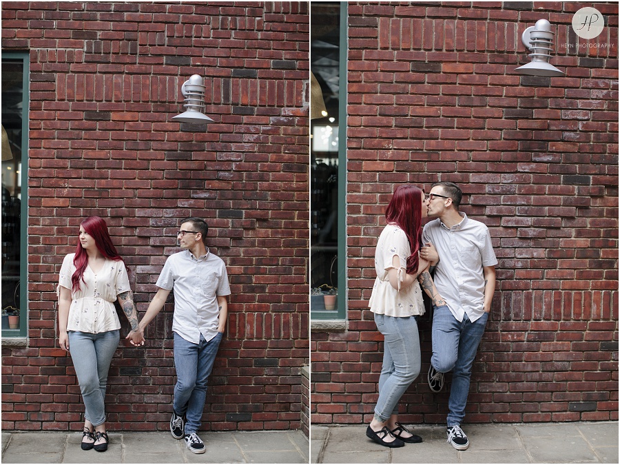 engaged couple in front of brick wall at downtown asbury park engagement session 