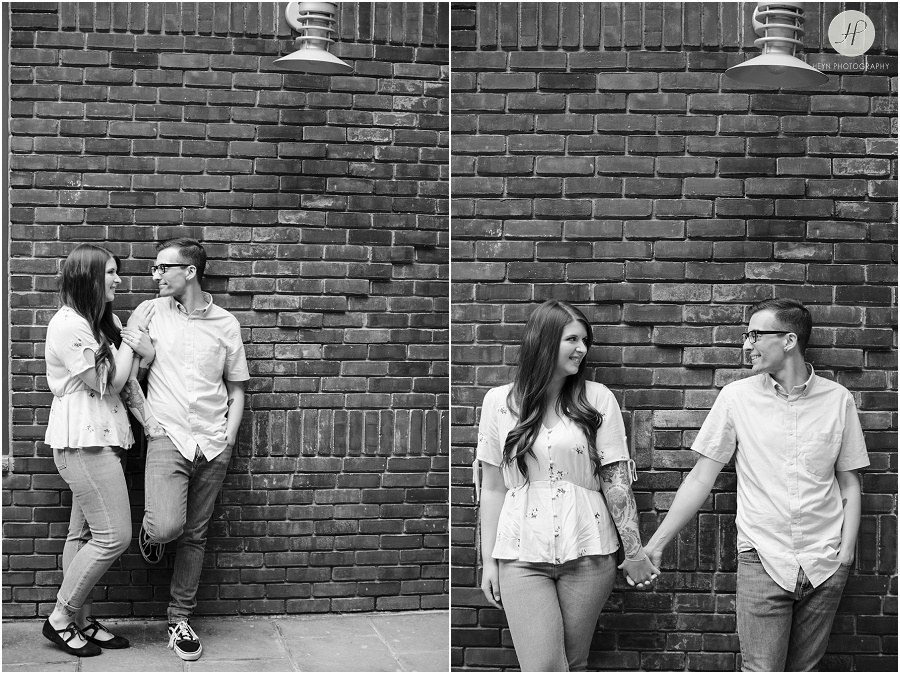 black and white of engaged couple in front of brick wall at downtown asbury park engagement session 