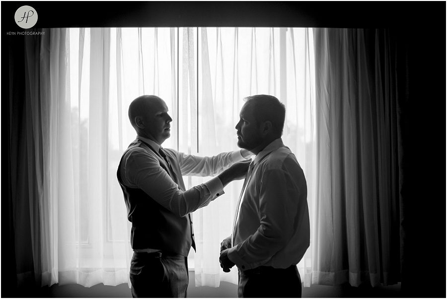 black and white of best man helping groom put on tie for clarks landing wedding 