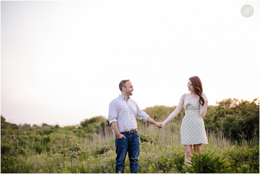  engaged couple holding hands in tall grass at dusk in downtown spring lake engagement session
