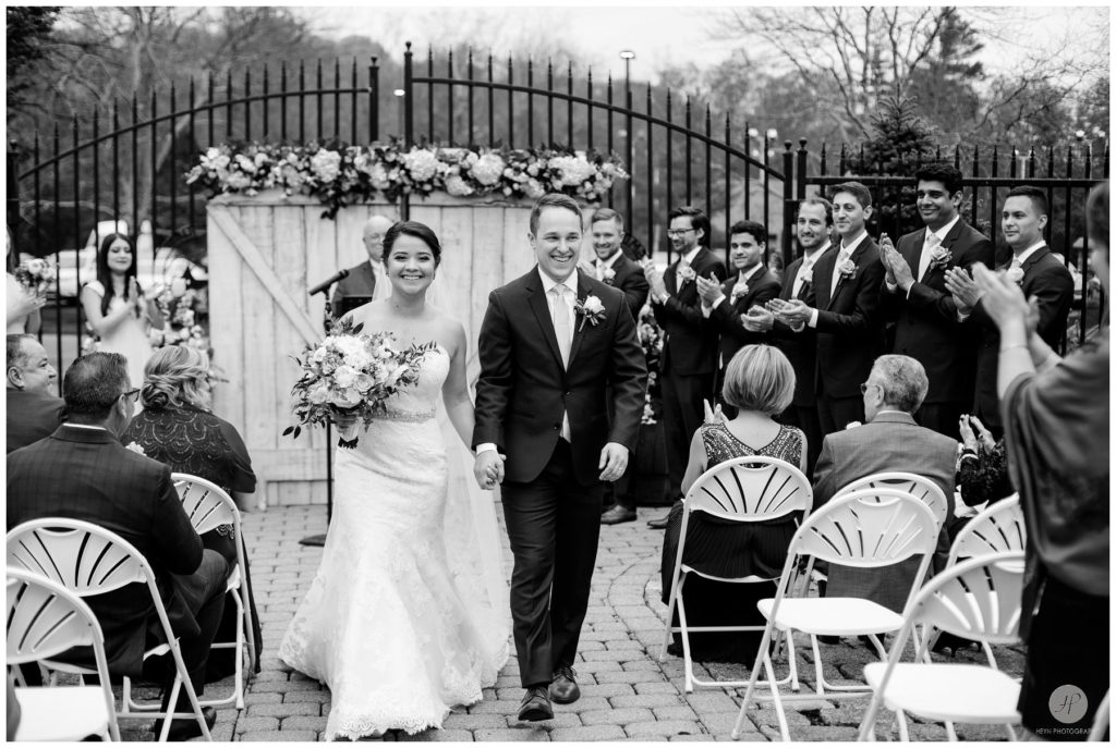 black and white photo of bride and groom walking out at outdoor wedding ceremony at smoke rise village inn