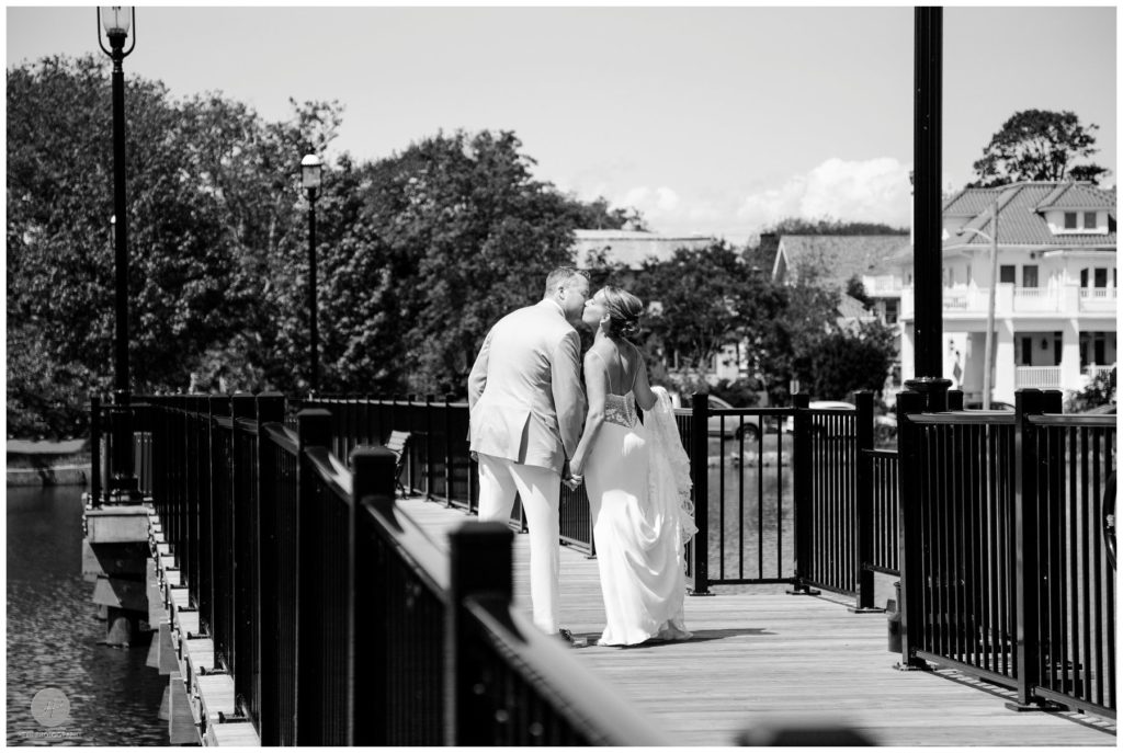 bride and groom kiss on bridge in sunset park