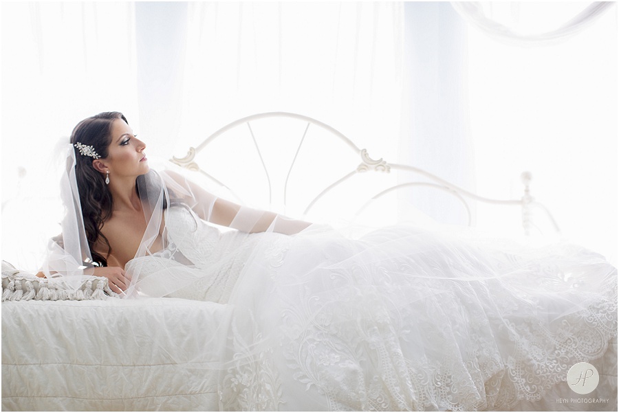 bride posing on bed in calla blanche dress at clarks landing yacht club