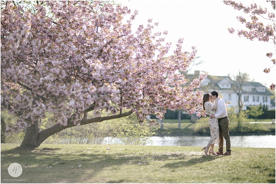 couple kissing by cherry blossom tree at spring lake engagement session in new jersey 