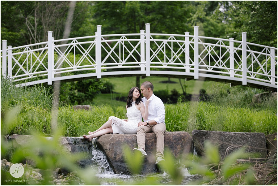 engaged couple on rocks under bridge at sayen gardens new jersey shoot 